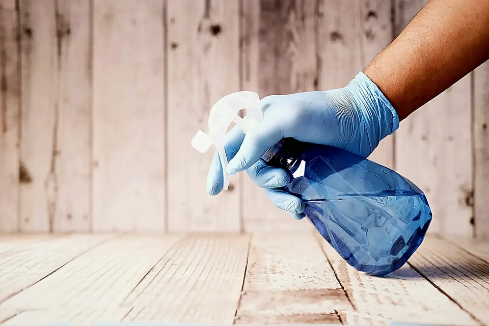 Gloved hand holding a spray bottle for recurring home cleaning upkeep