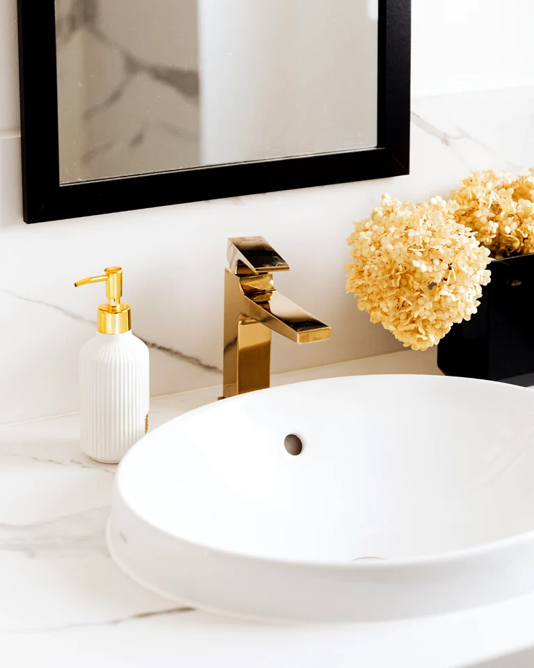 Polished white bathroom sink with gold faucet